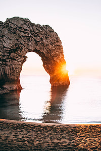 arch-shaped brown rock formation in ocean thumbnail