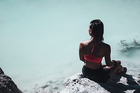 woman in pink and black swimsuit sitting on gray rock thumbnail