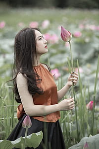 Woman in Brown Shirt Holding Pink Petaled Flower thumbnail