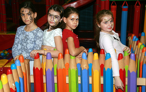 four girls standing beside crayon-themed fence thumbnail