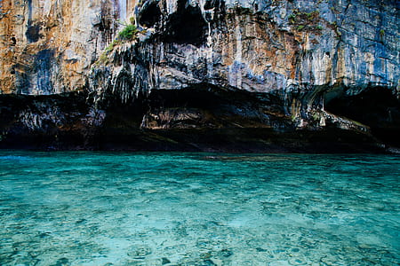 body of water below brown rock thumbnail