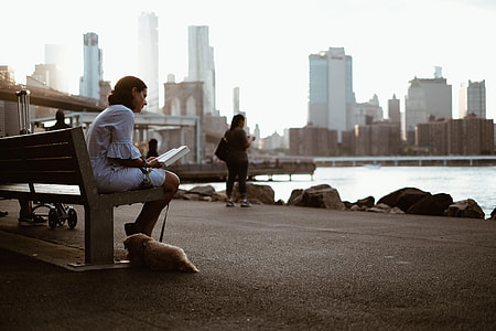 shallow focus of woman in white top sitting on gray concrete bench during daytime thumbnail