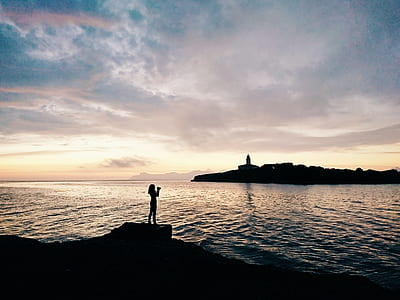 silhouette of woman standing on rock cliff thumbnail