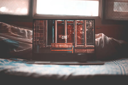 black Dell laptop turn on place on bed near window thumbnail