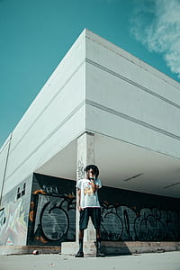 man standing behind building during daytime thumbnail