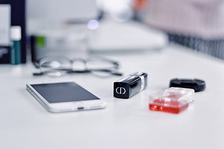 smartphone near fragrance bottle and lipstick on table thumbnail