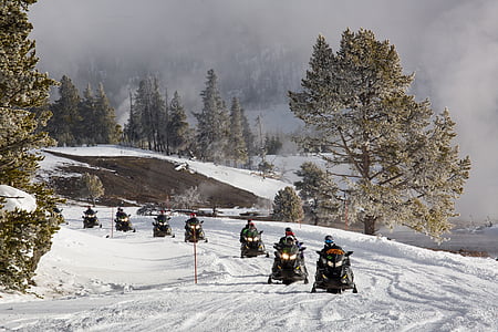 people riding snow mobiles on snow covered ground thumbnail