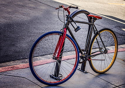 black fixie bike locked on black metal bike rack on side of road at daytime thumbnail