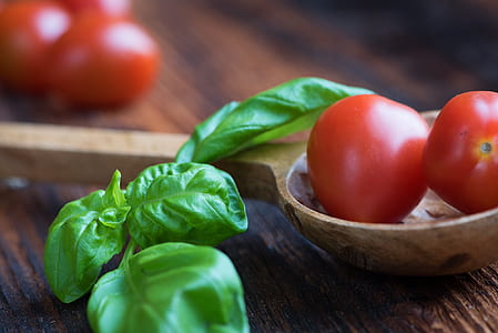 tomatoes and green leaves on top of brown wooden table thumbnail