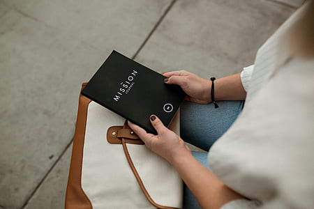 woman sitting on chair while holding a Mission titled book thumbnail
