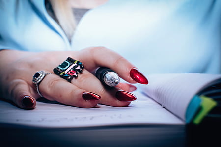 person with assorted rings holding ball-point pen thumbnail