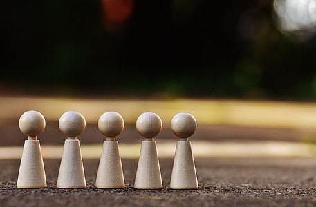 five wooden brown pawn pieces on the ground thumbnail