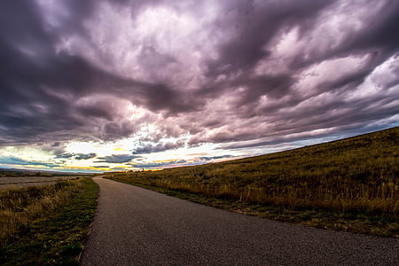 brown concrete rod beside grass field under gloomy sky thumbnail