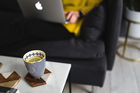 Young woman sitting on the sofa and working on her laptop thumbnail