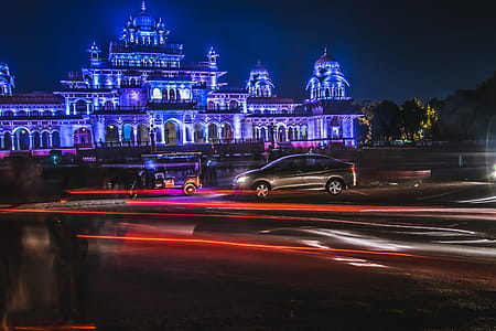 Grey Sedan and Red Auto Rickshaw in Front of Purple Mansion thumbnail