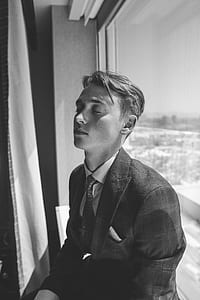 greyscale photo of man sitting in front of glass window thumbnail