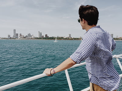 man leaning on white railing facing sea thumbnail