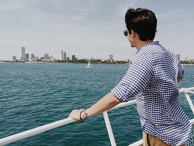 man standing at duck of boat watching the city thumbnail