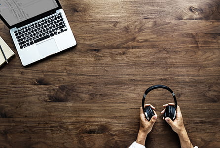 person holding black headphones on brown wooden surface thumbnail