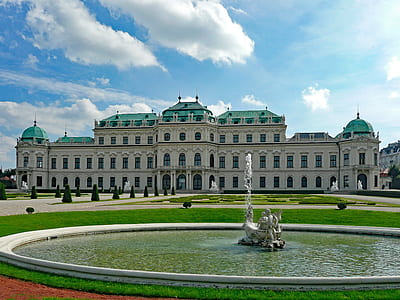 outdoor fountain near white and green building under blue and white sky at daytime thumbnail
