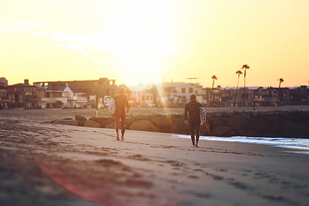 two men carrying surfboards during sunset thumbnail