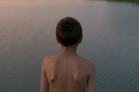 boy standing in front of body of water thumbnail
