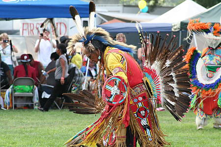 man wearing native American costume while standing on green grass during daytime thumbnail