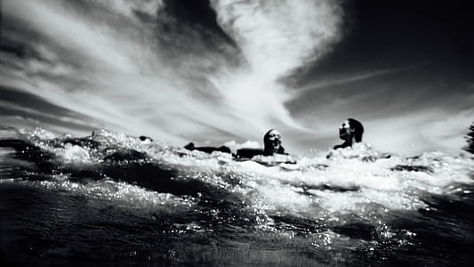 man and woman swimming under sky grayscale photo thumbnail