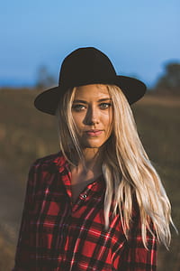 tilt shift lens photography of woman wearing red and black plaid button-up top and black hat thumbnail