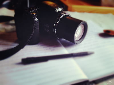 selective focus of black Nikon bridge camera on printed notebook thumbnail
