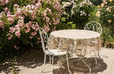 beige floral table cover on round white patio table beside two chairs thumbnail