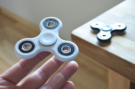 person holding fidget hand spinners near table thumbnail