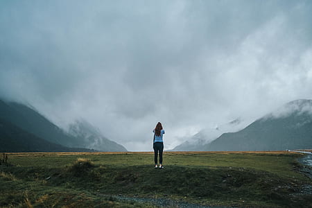 woman standing on field under gray sky during daytime thumbnail