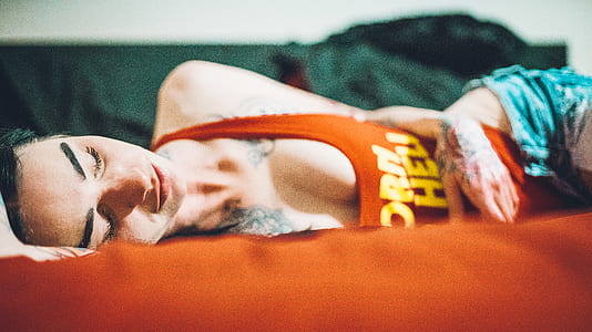 woman wearing orange tank top lying on the bed thumbnail