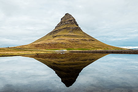 brown mountain near body of water during daytime thumbnail