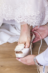 person fitting shoe on woman wearing wedding dress thumbnail