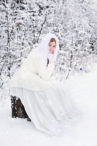woman sitting on a tree trunk in a snowfield thumbnail