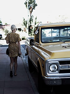 woman standing near yellow single-cab pickup truck thumbnail