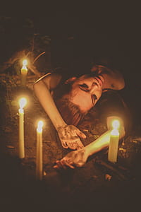 woman lying on soil with four lighted white candles thumbnail
