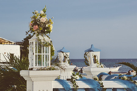 photography of white and pink rose flowers on white candle lantern during daytime thumbnail