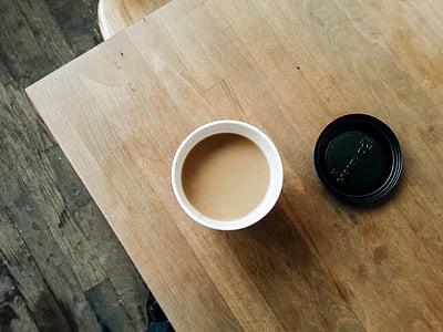filled white disposable coffee cup with lid on table thumbnail