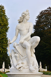 man sitting on dog statue near trees at daytime thumbnail