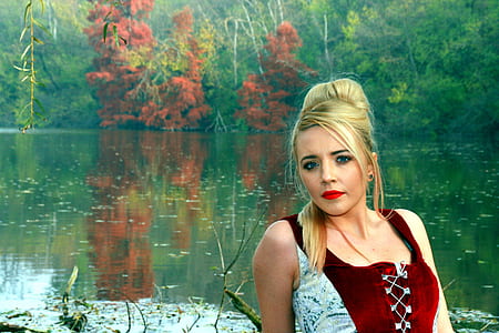 woman in red and white top near green body of water thumbnail