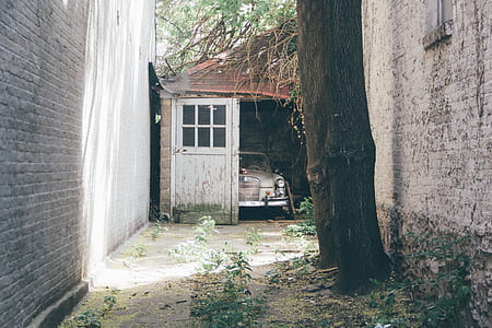 vintage white car inside of opened garage by the alley thumbnail