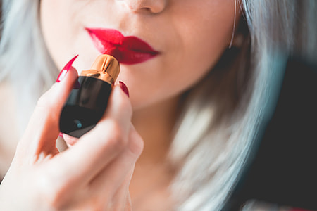 Young & Smiling Woman Applying Red Lipstick thumbnail