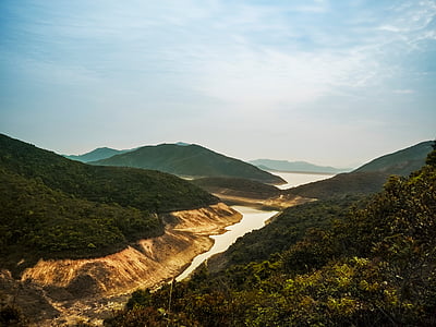 river between hills under cloudy sky thumbnail