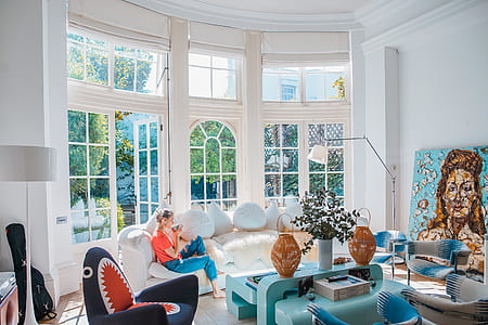 woman wearing blue jeans and red top sitting on white couch during daytime thumbnail