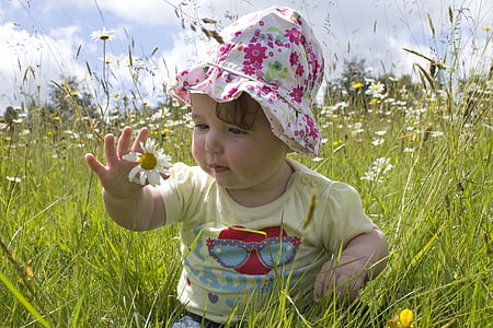 photo of baby sitting on white petaled flower field during daytime thumbnail