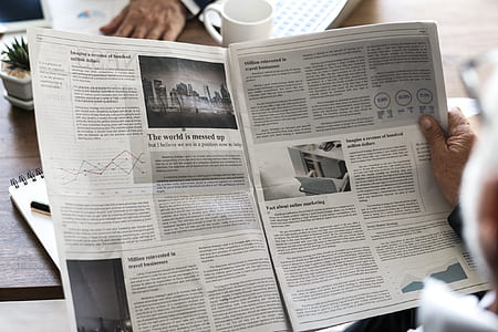 person holding newspaper in front of cup thumbnail