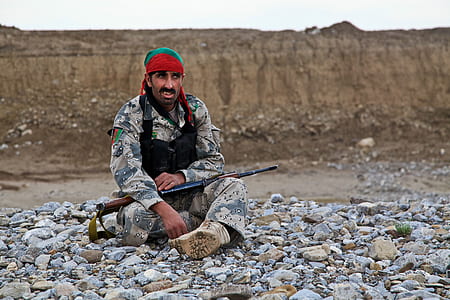 military man sitting on rocks thumbnail